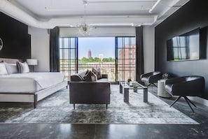 Living area with ample seating and a large bed in front of large double doors to the balcony.