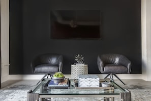 Wall-mounted TV rests above two leather armchairs in this Ponce City Market rental, and in front of a coffee table.