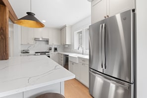 The fully equipped kitchen with quartz countertops is ready for you - bon appetit!