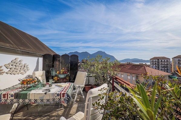 Ca. 10 m² großer Sonnenbalkon mit Blick auf die Dächer von Intra, den See und die gegenüberliegenden Berge