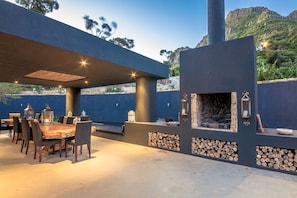 Braai/grill adjoining outdoor dining area w/table made from trees on property