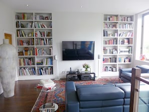 Living area, so many books! Large screen TV, and view of the private garden.