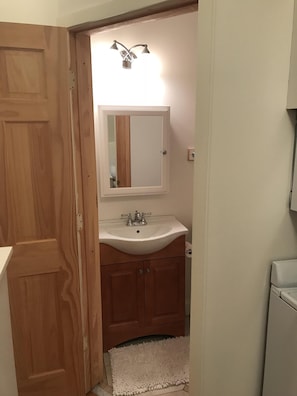 Full bathroom with privacy door, sink vanity, toilet, shower stall.