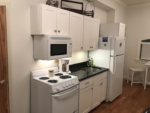 Cozy efficiency kitchen. Full size appliances: microwave, stove/oven, fridge.