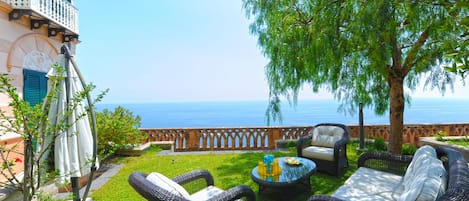 Private garden  with sea view and furnished with sofa and umbrella