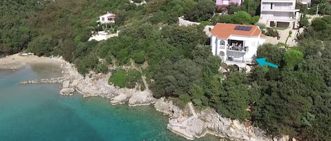 Villa am Meer mit Blick in die Bucht mit Sandstrand; der Pfeil markiert das Ap.1