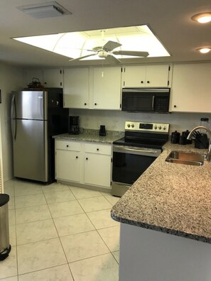 Kitchen with new stainless refrigerator and new stainless steel glass top stove.