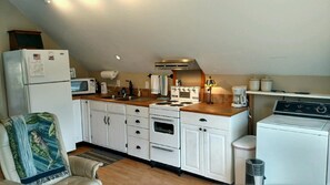 Full kitchen with dishes, glasses, towels, coffee pot and range with oven