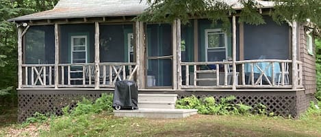 Metz Camp with screened porch and dining table and charcoal grill outside.