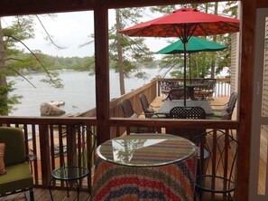 Screened porch leads to a deck overlooking the lake with tables for 12 people