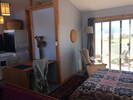 Living area with bed open. Table left. Washer, drier, edge of stove back left.