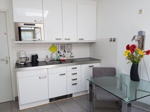 Kitchen top l to r microwave-oven, cabinet crockery and glasses, hood.
