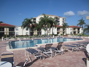 Large Pool with Lounge Chairs, Patio Tables with Umbrellas, and Electric Grill