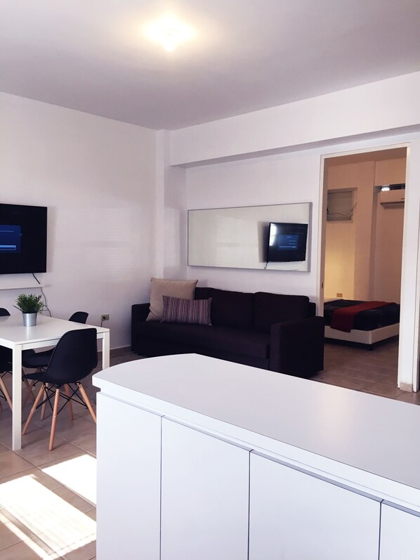 Area de comedor con 4 sillas, smart TV y esta proximo al area de cocina.