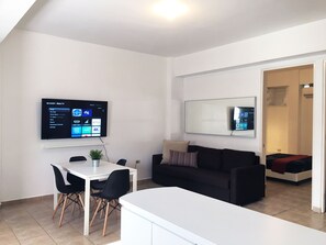Area de comedor con 4 sillas, smart TV y esta proximo al area de cocina.