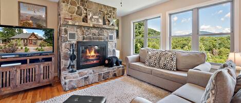 The living room features a large stone wood burning fireplace and a gorgeous view