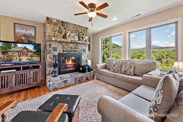 The living room features a large stone wood burning fireplace and a gorgeous view