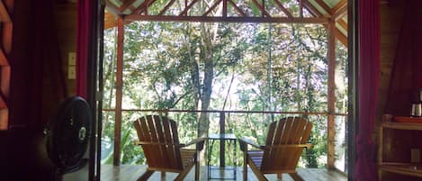 Large glass doors open to balcony with sitting are with tree house like views!