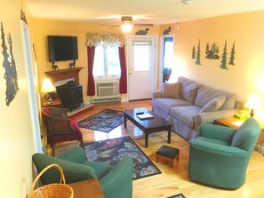 Large family room with gas stove, flat screen TV, and balcony access.