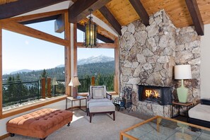 Enjoy the lake views in this spacious living room features a charming wood-burning fireplace and ample seating, creating the perfect space for family and friends to relax together