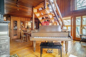 Living room piano is seen with dining area and sliding door to solarium behind