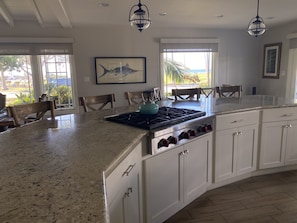 Alternate view of kitchen, with ocean view, range, and bar seating.