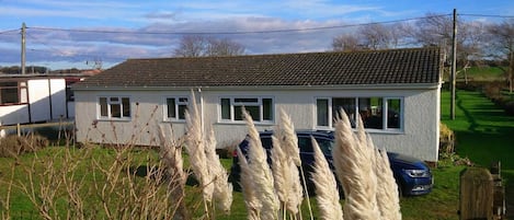 Front of property from the road showing  parking at the front and large garden.