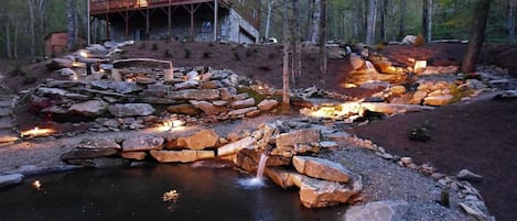 Waterfall and fire pit lit up at night