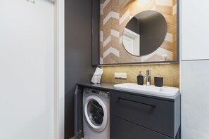 Bright bathroom with washing machine and shower cabin. 