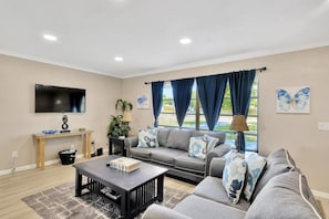The living room has a queen sleeper sofa bed, room darkening shades, and a large Smart TV.