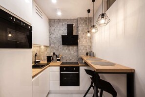 Functional kitchen with dining space and such appliances as kettle, oven, steam absorber, and microwave.