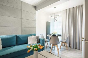 Bright and modern living room wit dining table, chairs, coffee table, and stylish double sofa bed.