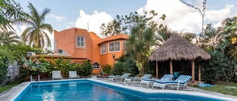 The large backyard has a pool, lots of seating, and a small shaded outdoor eating area