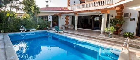 The pool is surrounded by lush gardens