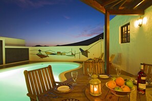 Private pool area with shaded table and Manrique style mural