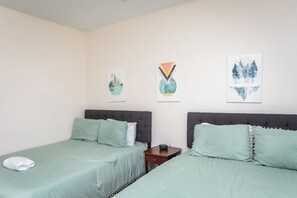 First bedroom with two queen beds featuring pillow-top mattresses, luxurious bedding, and a closet for storage.