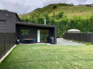 External area of the accomodation, with parking for 2 cars to the right, a covered outdoor seating area and bbq