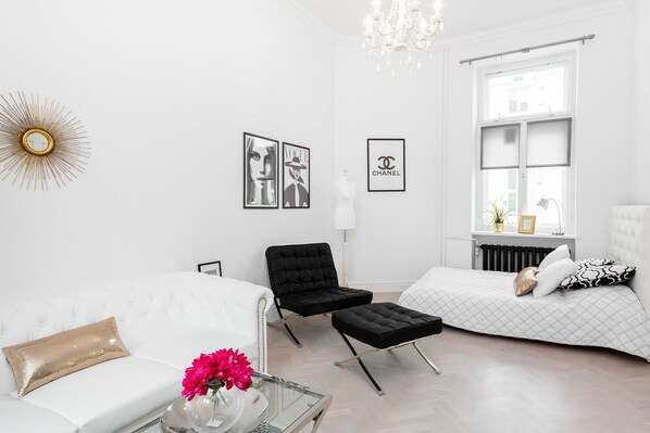 Bright and comfortable living area with an armchair, stylish sofa, and elegant bed for two people.