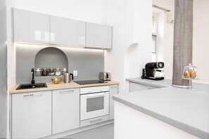 Bright and functional kitchenette with an oven, a coffee machine, and an electric kettle.