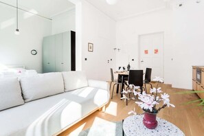 Spacious and functional living area with a capacious wardrobe, double sofa bed, double bed, dining table, coffee table, television, and cabinet.