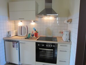 Einbauküche mit Vierplattenherd mit Backofen und Kühlschrank mit Gefreirfach