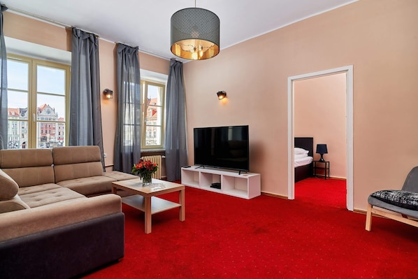 Atmospheric and elegant living room with stylish beige double sofa bed, coffee table, and large television.
