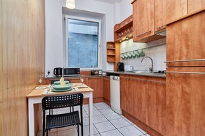 Independent kitchen with dining area for two people, wooden cabinets, and microwave.