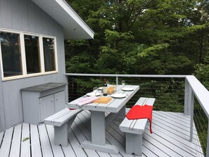 Huge wrap around deck with large picnic table, serving cabinet and propane grill