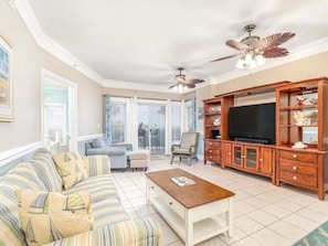 The living area with a sleeper sofa, flat screen TV, and balcony access