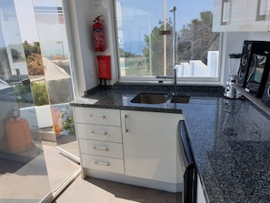 Outdoor kitchen by pool with stereo, dishwasher, fridge 