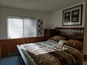 Master bedroom has a king bed and forest view.