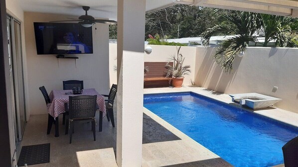 Pool area with fountain and coral stone deck, Smart TV and table