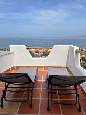 Lounge chairs by pool, view to Banderas Bay, sky
