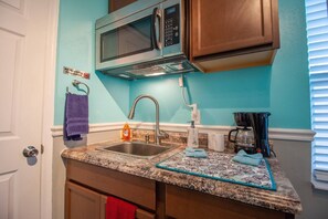 Kitchenette with microwave, coffee maker, sink and kitchen cabinets